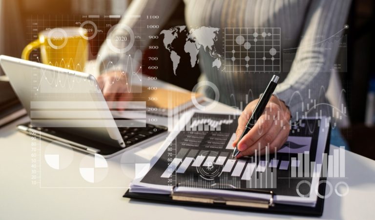 Personne travaillant sur des documents et un ordinateur portable, entourée d'une superposition numérique de graphiques et d'une carte du monde illustrant l'analyse de données.