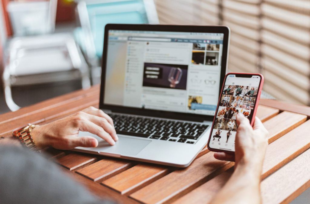 Photo d'un homme consultant ses réseaux sociaux sur son ordinateur et son téléphone